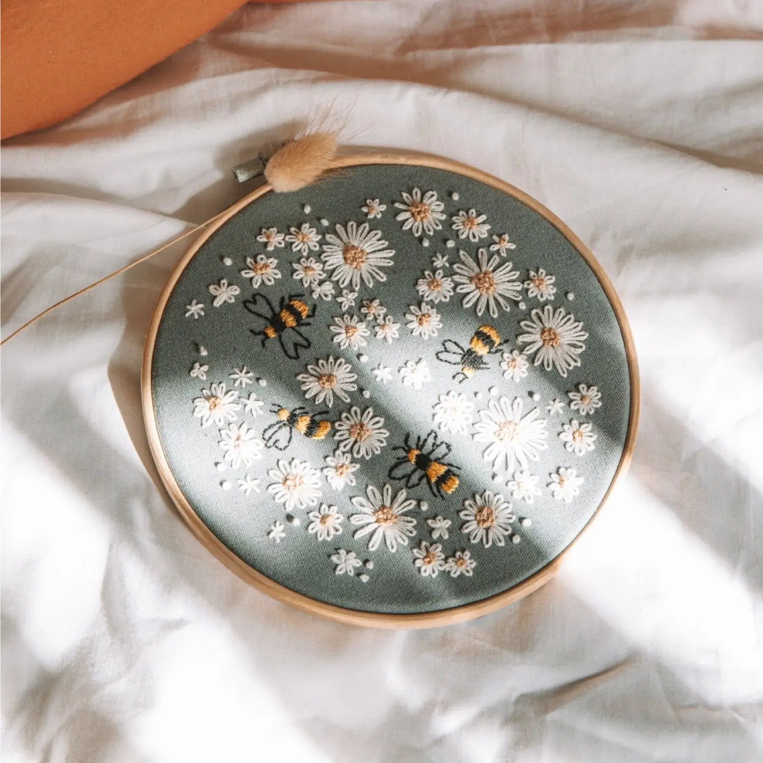 Embroidery hoop with floral and bee pattern on a white fabric background