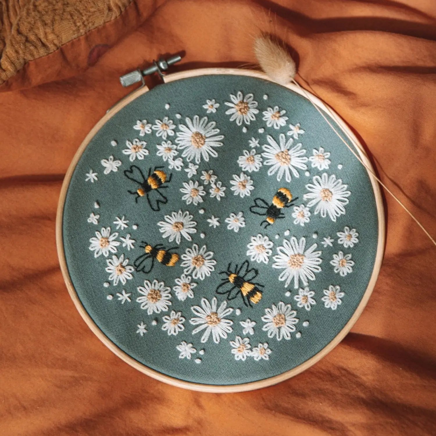 Embroidery hoop with floral and bee design on a fabric surface
