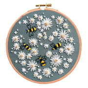 Embroidery hoop with floral and bee design on green fabric